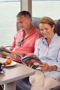 couple sitting and reading magazine in club class onboard condor liberation