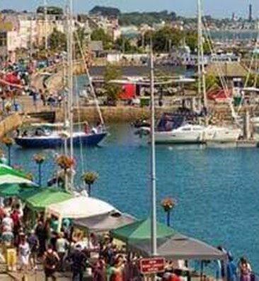 stalls and shopping with boats in the sea outside st peter port