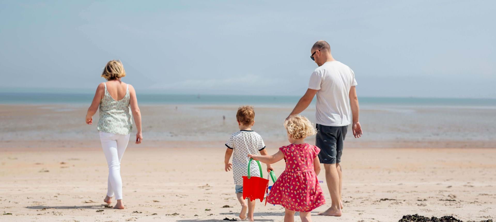 a family walking along the golden sands on a beach in jersey