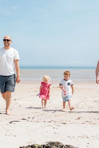 family walking on a beach walk jersey with white sand and blue skies
