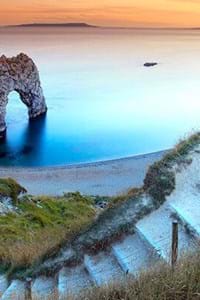 view with clifftop and golden sands with blue sea at durdle door dorset